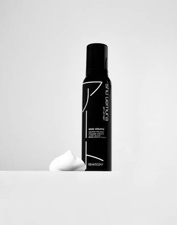 A black bottle of Shu Uemura Awa Volume Mousse with white foam next to it, displayed on a minimal white background.