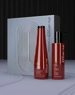 Shu Uemura Color Lustre shampoo and conditioner bottles in red, displayed next to a box with a blue rope pattern.